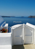 Traditional Greek houses in Oia, Santorini, Greece, are scattered on caldera on Santorini island. White houses with bright blue elements like roofs, windows, doors or fences on dark, almost black rocks of vulcano island Santorini, are trademark of Santorini, known worldwide.
