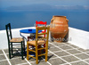 Chairs and table on the roof of traditional Santorini house in village of Firostefani, Santorini, Greece. Traditional Greek houses in Firostefani, Santorini, Greece, are scattered on caldera on Santorini island. White houses with bright blue elements like roofs, windows, doors or fences on dark, almost black rocks of vulcano island Santorini, are trademark of Santorini, known worldwide.
