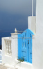 Traditional Greek houses in Oia, Santorini, Greece, are scattered on caldera on Santorini island. White houses with bright blue elements like roofs, windows, doors or fences on dark, almost black rocks of vulcano island Santorini, are trademark of Santorini, known worldwide.
