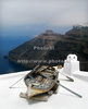Old boat on roof of traditional Santorini house in village of Firostefani, Santorini, Greece. Traditional Greek houses in Firostefani, Santorini, Greece, are scattered on caldera on Santorini island. White houses with bright blue elements like roofs, windows, doors or fences on dark, almost black rocks of vulcano island Santorini, are trademark of Santorini, known worldwide.
