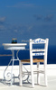 Chairs on roof of traditional Santorini house in Firostefani village on Santorini island, Greee. Traditional Greek houses in Firostefani, Santorini, Greece, are scattered on caldera on Santorini island. White houses with bright blue elements like roofs, windows, doors or fences on dark, almost black rocks of vulcano island Santorini, are trademark of Santorini, known worldwide.

