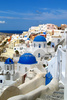Traditional Greek houses in Oia, Santorini, Greece, are scattered on caldera on Santorini island. White houses with bright blue elements like roofs, windows, doors or fences on dark, almost black rocks of vulcano island Santorini, are trademark of Santorini, known worldwide.
