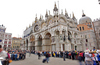People are storming Piazza San Marco while others are already queing to enter Basilica of Saint Mark (officially known in Italian as the Basilica Cattedrale Patriarcale di San Marco and commonly known as Saint Mark Basilica) during early morning hours. Piazza San Marco (often known in English as St Mark Square), is the principal public square of Venice, Italy, where it is generally known just as the Piazza. All other urban spaces in the city (except the Piazzetta and the Piazzale Roma) are called campi (fields). The Piazzetta (the little Piazza) is an extension of the Piazza towards the lagoon in its south east corner (See plan). The two spaces together form the social, religious and political centre of Venice and are commonly considered together.
