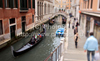 People are enjoying moments on canals of Venice, Italy, traveling around with gondolas. The gondola is a traditional, flat-bottomed Venetian rowing boat, well suited to the conditions of the Venetian lagoon. For centuries gondolas were the chief means of transportation and most common watercraft within Venice. In modern times the iconic boats still have a role in public transport in the city, serving as traghetti (ferries) over the Grand Canal.
