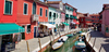 Burano is an island in the Venetian Lagoon, Italy. Like Venice itself, it could more correctly be called an archipelago of four islands linked by bridges. It is situated near Torcello at the northern end of the Lagoon, and is known for its lacework and brightly colored homes. <br> Small, brightly-painted houses on Burano follow a specific system originating from the golden age of its development. If someone wishes to paint their home, one must send a request to the government, who will respond by making notice of the certain colors permitted for that lot.
