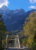 Bridge leading over Sava river near village of Martuljek, Slovenia, on sunny autumn day. In background is north wall of Spik mountain covered with early snow.

