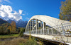 Bridge leading over Sava river near village of Martuljek, Slovenia, on sunny autumn day. In background is north wall of Spik mountain covered with early snow.
