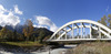 Bridge leading over Sava river near village of Martuljek, Slovenia, on sunny autumn day. In background is north wall of Spik mountain covered with early snow.
