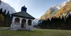 Mary Help chapel in Tamar is in shadow thrown by nearby mountains on early autumn morning, when temperatures fall under freezing level. mountaineering
