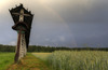 Hayrack and shrines with the crucifix under the rainbow on fields near Preddvor, Slovenia, on summer evening of 13th June 2014, after rain storm just passed the area.
