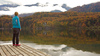 Woman on shore of the Bohinj lake in Bohinj, Slovenia, surrounded by trees already painted in autumn colors on Saturday, 17th of October 2015.
