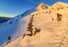 Sun is rising over mountains above Ljubelj road pass near Trzic, Slovenia, on early morning of 17th of December 2020, while ski mountaineers are climbing toward their goal. Sunrise is seen from slopes of Vrtaca mountain during ski mountaineering tour.