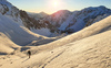 Sun is rising over mountains above Ljubelj road pass near Trzic, Slovenia, on early morning of 17th of December 2020, while ski mountaineers are climbing toward their goal. Sunrise is seen from slopes of Vrtaca mountain during ski mountaineering tour.