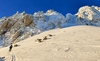 Sun is rising over mountains above Ljubelj road pass near Trzic, Slovenia, on early morning of 17th of December 2020, while ski mountaineers are climbing toward their goal. Sunrise is seen from slopes of Vrtaca mountain during ski mountaineering tour.